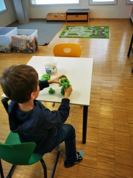 Ein Junge, der mit einem grünen Spielzeug an einem Tisch sitzt